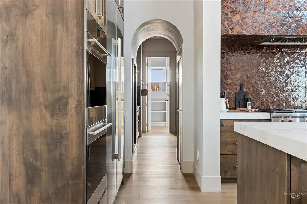 Arched hallway off a kitchen with a walnut cabinet wall