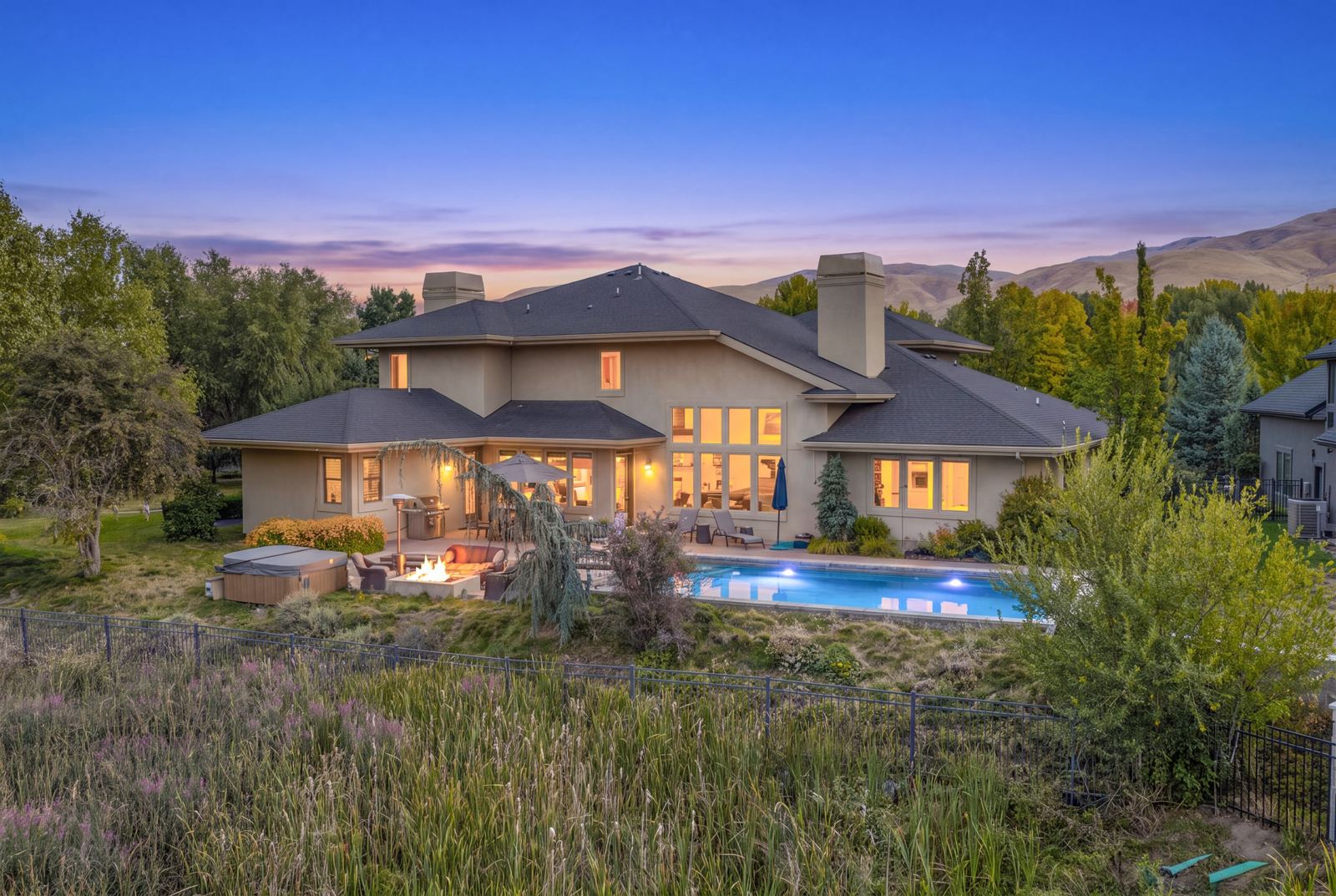 Twilight view of a Boise home with a pool and the foothills behind it